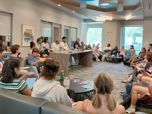 Students sit in a large circle in a campus lounge as members of the Mohamed Abozekry Sextet speak from a table at the front of the room. The musicians and professor lead a discussion about Arabic instruments and jazz fusion as part of a Contemporary Muslim Societies class.