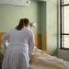 a physician in a white coat caring for a patient in a hospital bed