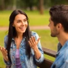 Woman talking to a man sitting on a bench